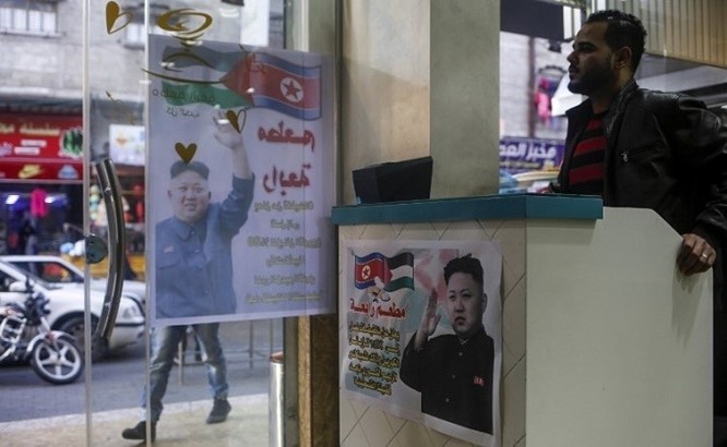 Palestyński kasjer czeka przy wejściu do restauracji Rabaa w obozie dla uchodźców Dżabalia w północnej Strefie Gazy 17 grudnia 2017 r. obok plakatów przedstawiających przywódcę Korei Północnej Kim Dzong-Una i tekstu po arabsku: „Specjalne zniżki sięgające 80 procent dla koreańskich patronów, w uznaniu dla roli koreańskiego przywódcy w naszej sprawie palestyńskiej”. (Źródło: AFP/Mohammed Abed, 2017)